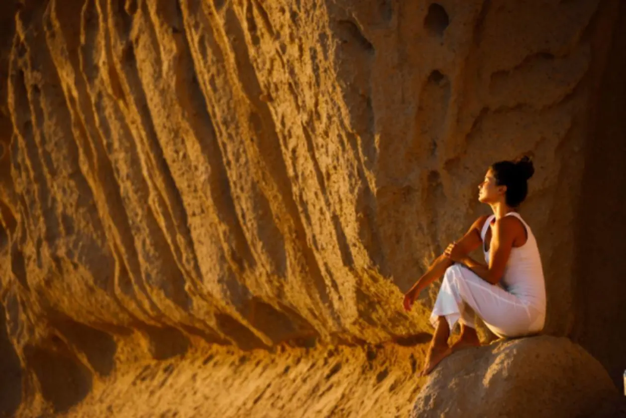 Woman with eyes closed by rock formation